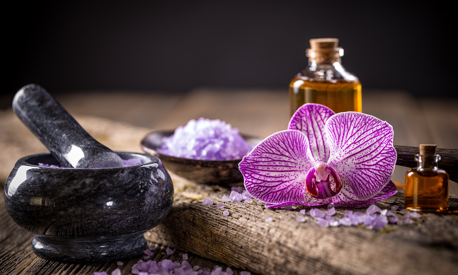 violet flower next to essential oil bottle